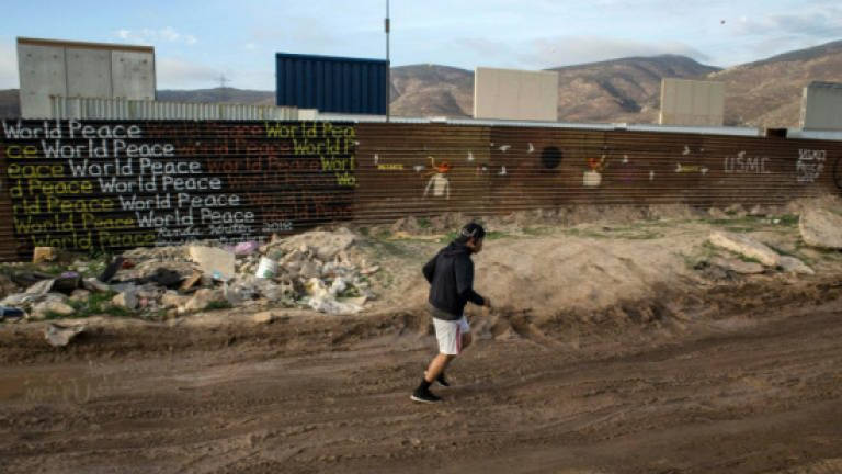 Undaunted by Trump's wall, migrants vow to go over it