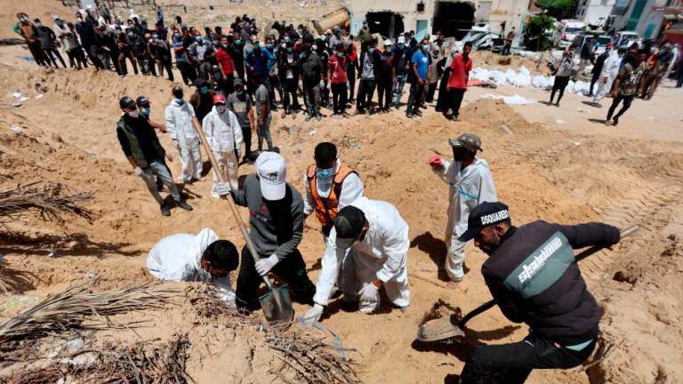 People work to move into a cemetery bodies of Palestinians killed during Israel’s military offensive and buried at Nasser hospital, amid the ongoing conflict between Israel and the Palestinian Islamist group Hamas, in Khan Younis in the southern Gaza Strip, April 21, 2024/REUTERSPix