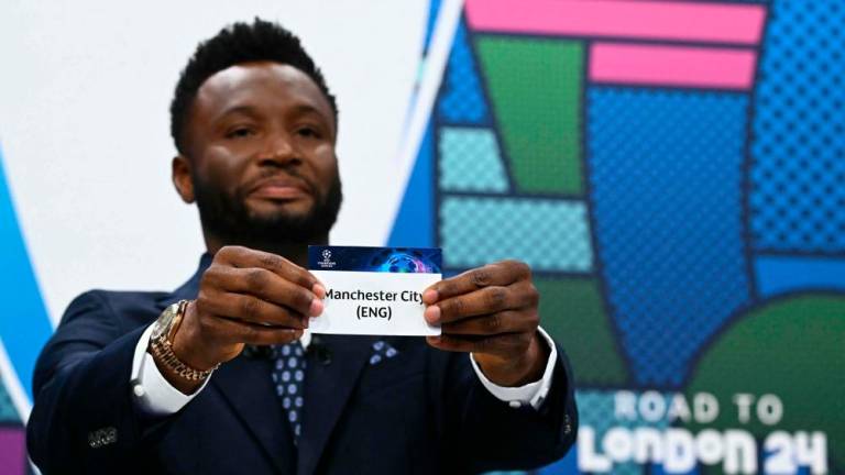 Former Nigerian footballer John Obi Mikel holds the paper slip of Manchester City during the 2023-2024 UEFA Champions League football tournament quarter-finals and semi-finals draw at the House of European Football in Nyon, on March 15, 2024/AFPPix