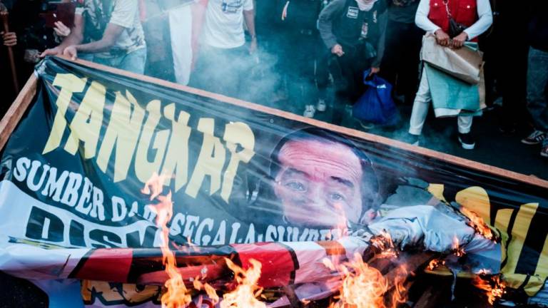 Demonstrators burn a billboard with a portrait of Indonesia’s President Joko Widodo during a protest against the results of the recent presidential election as the Constitutional Court rules on the petitions of ex-presidential candidates in Jakarta on April 22, 2024/AFPPix