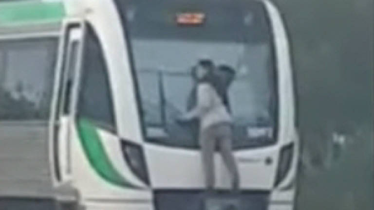 Man hitches free ride on train by clinging to wipers (Video)