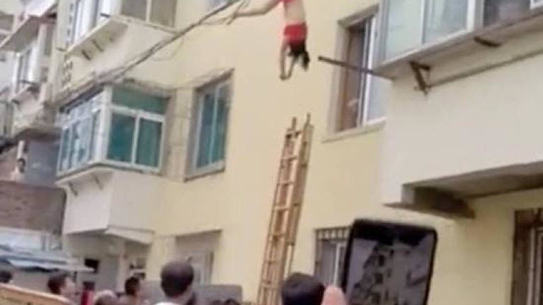 (Video) Woman falls from 5th floor, escapes death after getting tangled up in power line