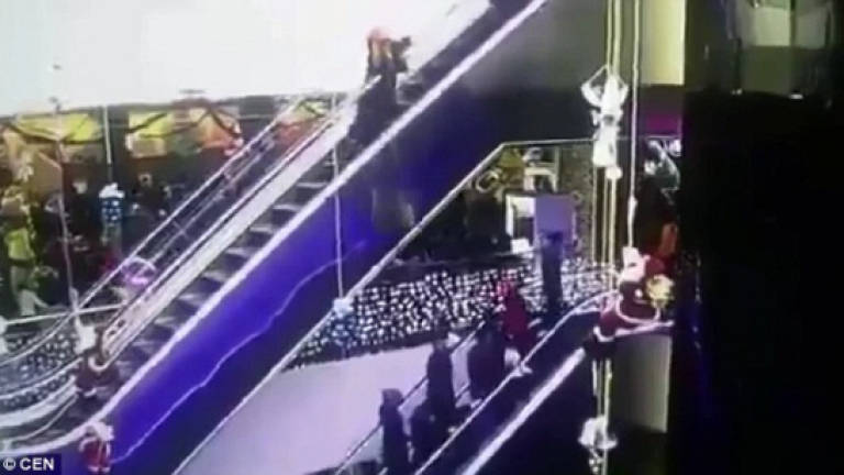 (Video) Mother drops her baby as her dress gets stuck in an escalator
