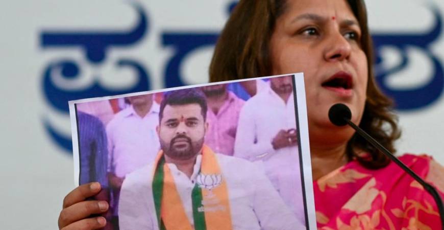 Congress spokesperson Supriya Shrinate shows a photograph featuring JD(S) MP Prajwal Revanna (L) who was summoned for alleged sexual abuse case, at a press conference in Bengaluru on May 1, 2024. - AFPPIX