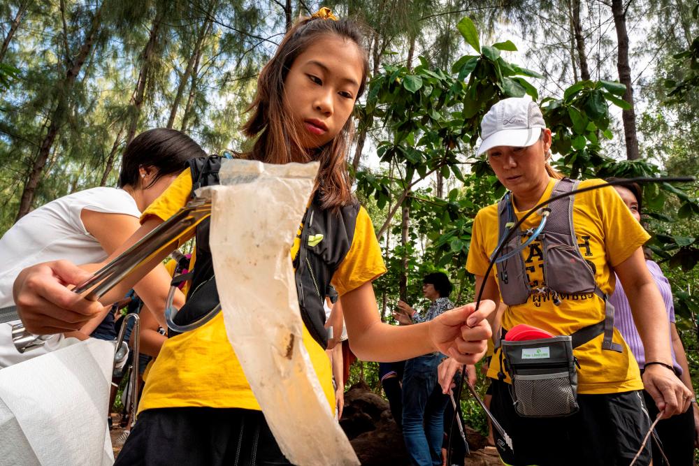 12-year-old Ralyn Satidtanasarn, known by her nickname Lilly, collects plastic waste during the Trash Hero cleaning initiative. — AFP