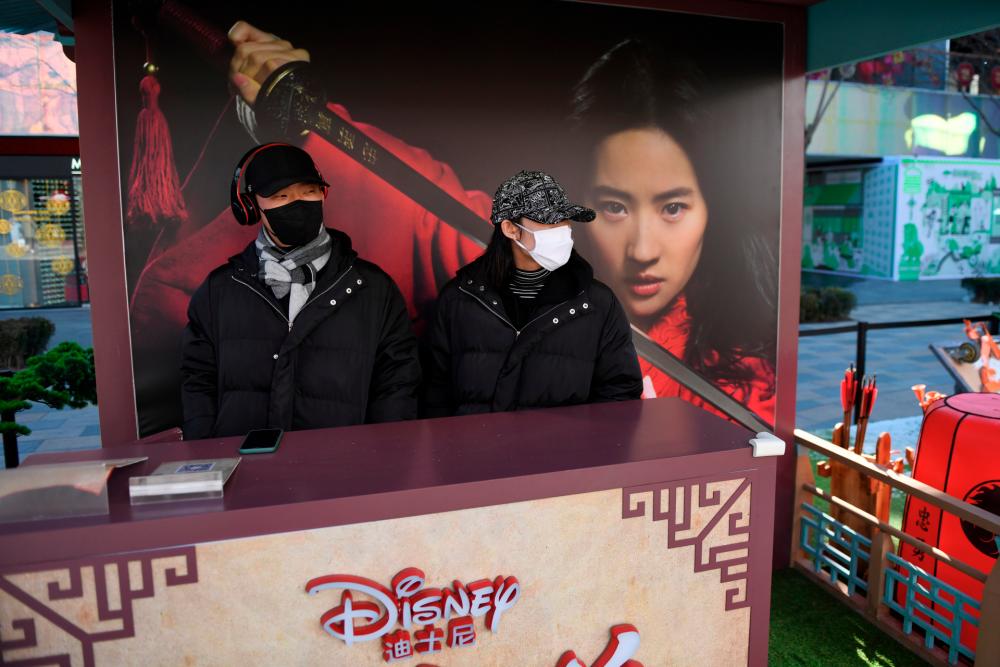 Two workers wearing face masks manning a promotional stand for the Disney move “Mulan” in an almost empty shopping mall in Beijing.