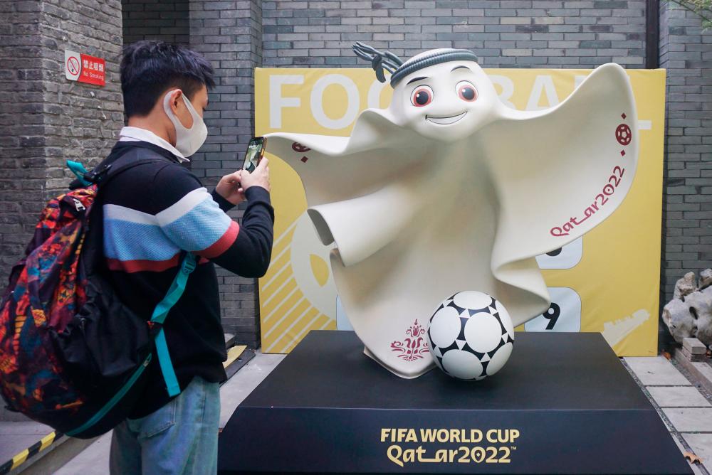 $!A man taking photos of the mascot of the Qatar 2022 FIFA World Cup football tournament outside a souvenir store in Hangzhou in China’s eastern Zhejiang province. – AFPPIX