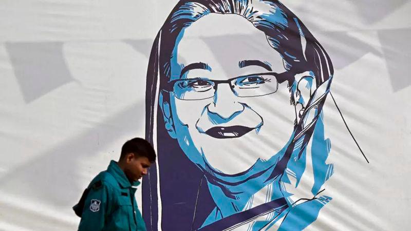 A policeman walks past a portrait of Bangladesh’s Prime Minister Sheikh Hasina in Dhaka on 8 January 2024. © Indranil Mukherjee, AFP