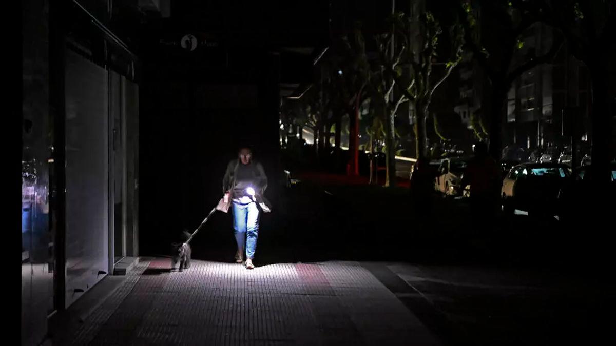 A woman uses her phone’s flashlight while she walks her dog in the dark during the massive power cut in Spain. © Miguel Riopa, AFP