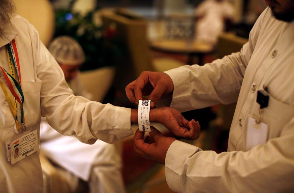 Saudi official adjusts an electronic bracelet given to pilgrims by Saudi authorities ahead of the annual Hajj. © AHMAD GHARABLI / AFP