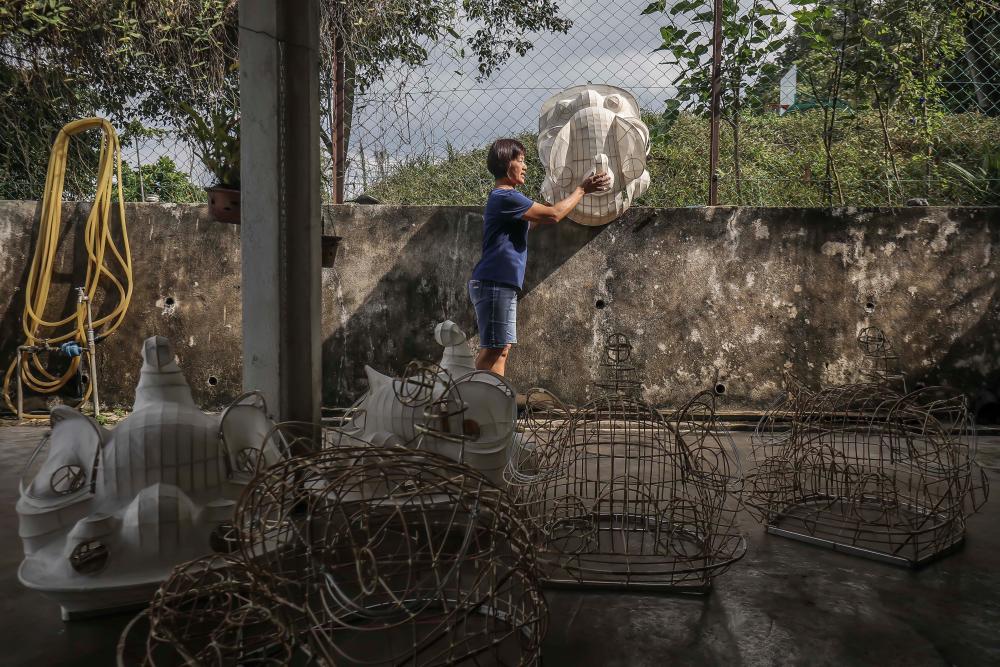 $!A woman is applying bamboo paper and gauze to a lion head frame to strengthen it. Then she takes it out to be dried by the sun at her home. ADIB RAWI YAHYA/THESUN