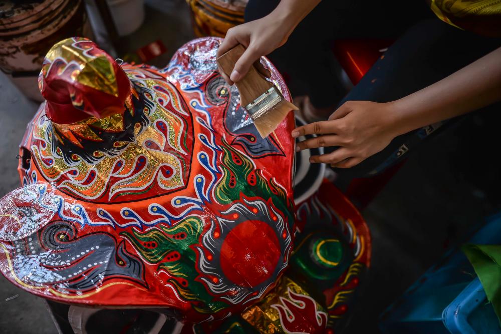 $!Once the paint has dried, a worker then applies lacquer onto the lion head to ensure that there is a protective layer and the colours stay vibrant and shiny for a long time. ADIB RAWI YAHYA/THESUN
