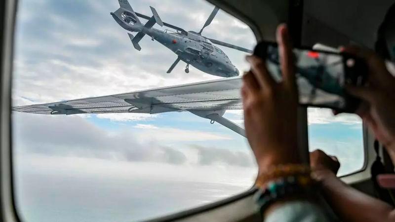 An aircraft identified by the Philippine Coast Guard as a Chinese Navy helicopter (L) flies near a plane carrying journalists over the contested Scarborough Shoal in the South China Sea © Jam STA ROSA / AFP