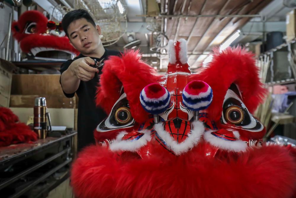 $!After applying the varnish, Wong then applies the fur, ribbon and bulbous fur balls onto certain parts of the lion head and shapes the fur as a final touch-up before it is sold to customers. ADIB RAWI YAHYA/THESUN