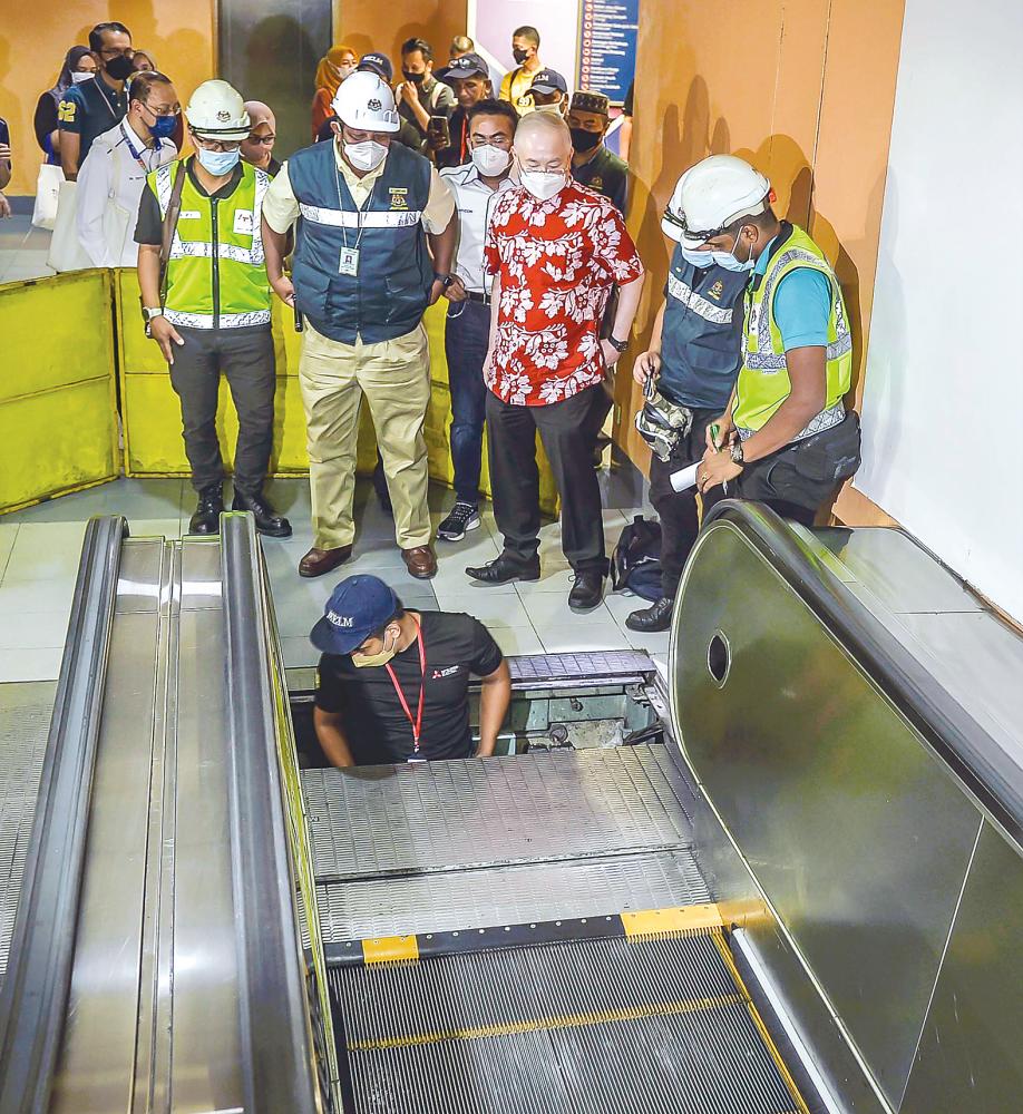 Wee (in red shirt) checking an escalator being repaired at the Ampang Park LRT station yesterday. – ADIB RAWI YAHYA/THESUN