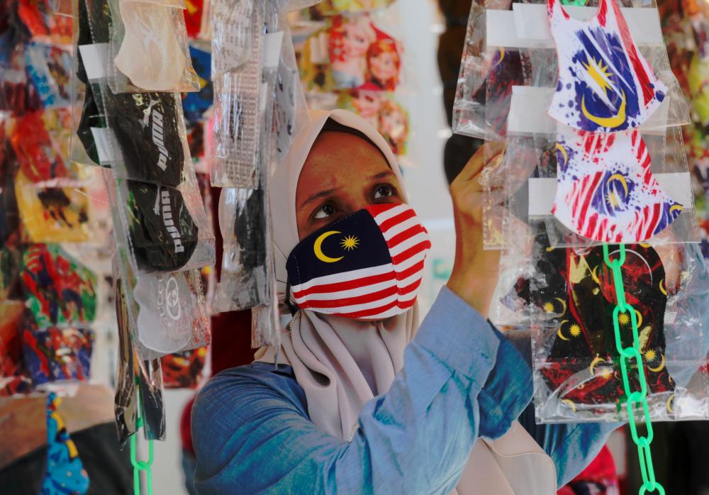 $!A trader selling fancy face masks at a stall in Jalan Tunku Abdul Rahman, Kuala Lumpur. – ASYRAF RASID/THESUN