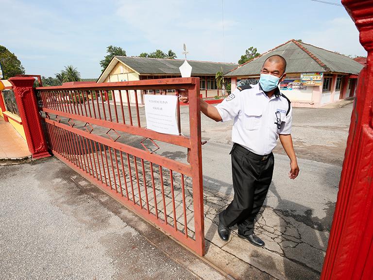 $!SK Hosba security guard Mohd Hadi Ahmad closing the school gate after educational institutes in the Kubang Pasu district were ordered to close following the implementation of an enhanced movement control order yesterday. – MASRY CHE ANI/THESUN