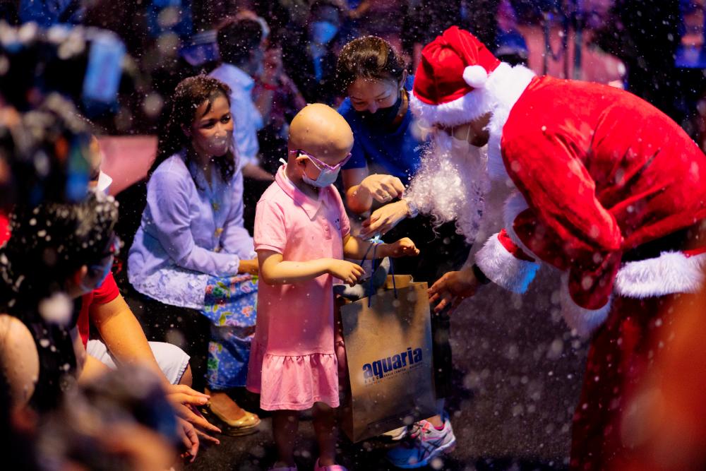 $!A special gift-giving surprise by Aquaria KLCC’s in-house Santa Claus while it snowed in Aquaria KLCC