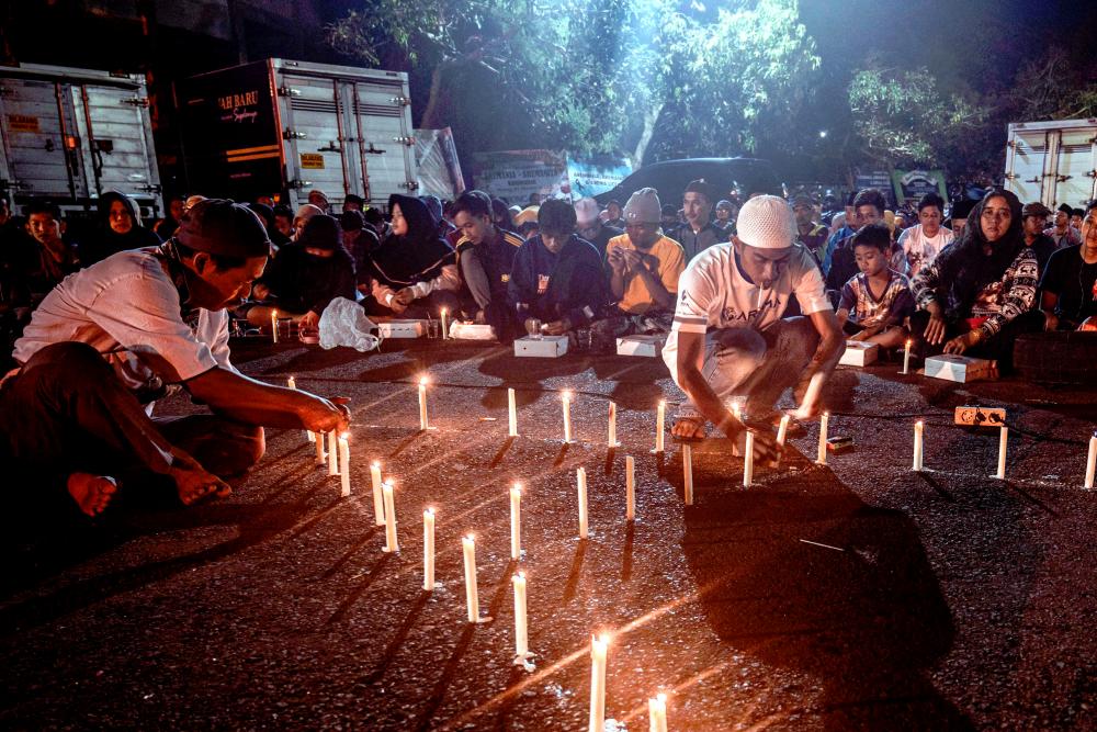 People and football supporters hold candlelight vigil for victims of a stampede at Kanjuruhan stadium in Malang/AFPPIX