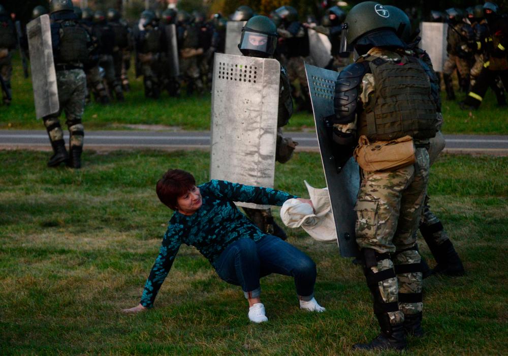 A woman falls in front of Belarusian policemen during a rally to protest against the inauguration of Alexander Lukashenko and against presidential election results in Minsk, Belarus, 23 Sept 2020. — AFP