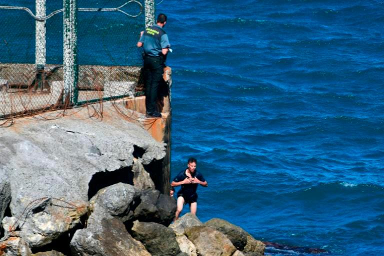 Migrants trying to enter either by scaling the tall barrier fence or swimming. — AFP