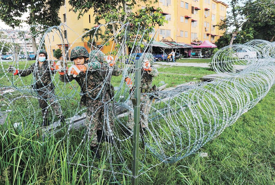Soldiers installing barbed wire around a residential complex in Kuala Langat, Selangor after three locations in the district were placed under a semi-enhanced movement control order. – Sunpix by Asyraf Rasid