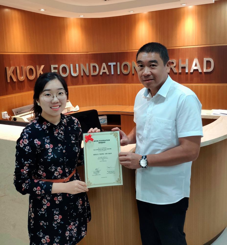 Kuok Foundation general manager Ng Teck Seng presents a scholarship to student Kelly Wong.
