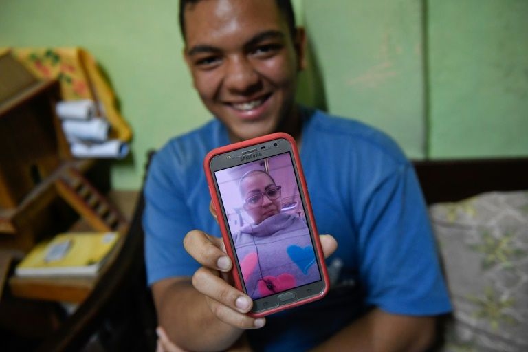 Venezuelan Frankeiber Hernandez, 18, whose parents emigrated to Peru, shows a picture of his mother on his mobile phone at home in the Catia neighborhood in Caracas. — AFP