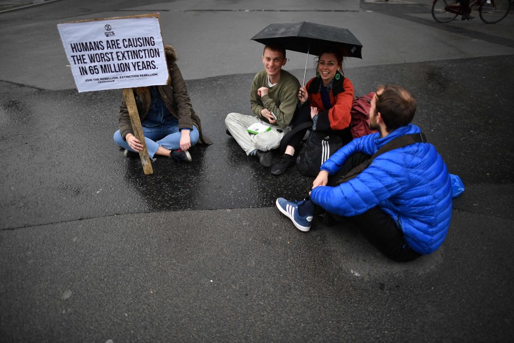 Protesters sit in a road near Parliament Square in central London on the second day of an environmental protest by the Extinction Rebellion group, April 16, 2019. — AFP