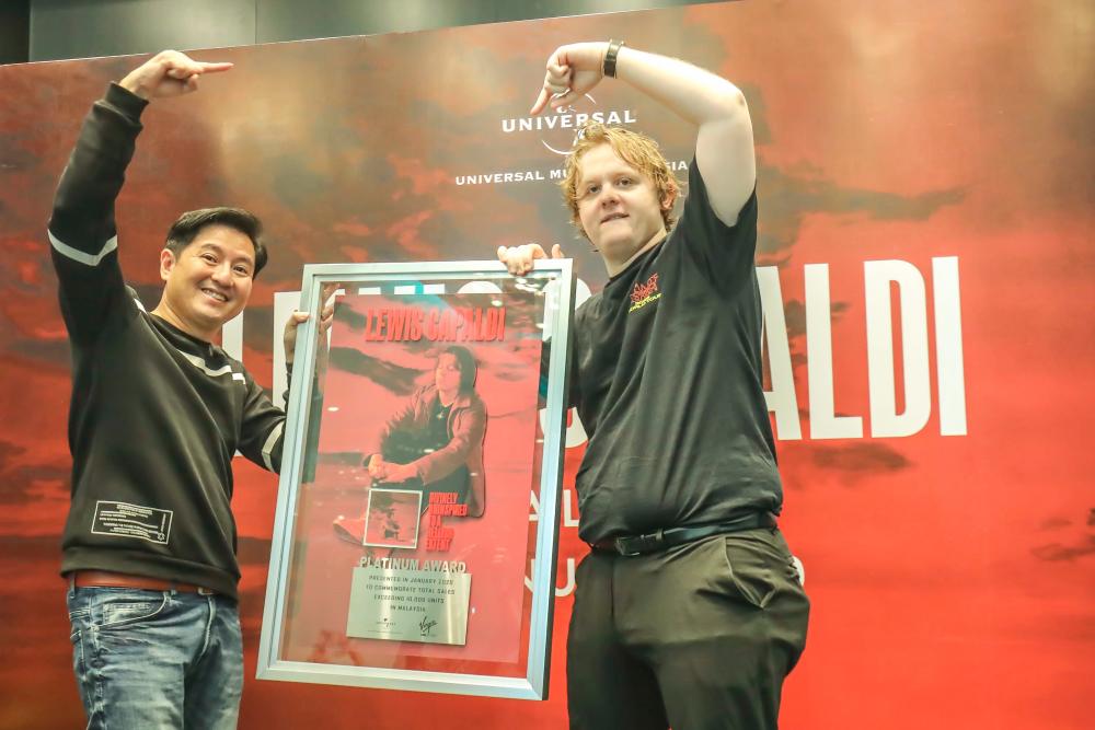 Universal Music Malaysia Managing Director, Kenny Ong (left) and Lewis Capaldi, posing with the Platinum Award which was presented to Capaldi for his album Divinely Uninspired to a Hellish Extent. – ADIB RAWI YAHYA/THESUN