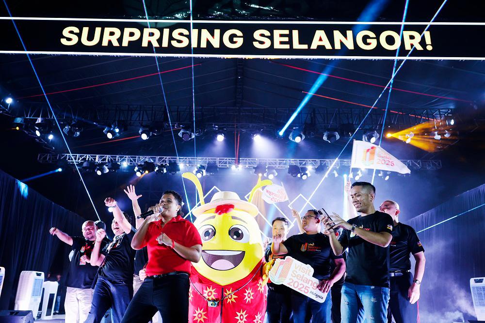 Aizat (in red) performing the official theme song, together with VSY 2025 mascot Spark the Firefly and other VIPs.