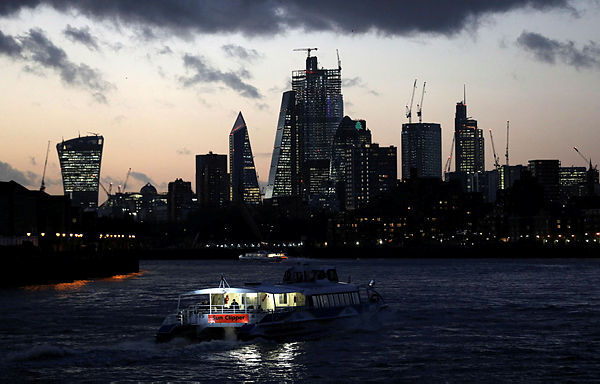 A river boat cruises down the River Thames as the sun sets behind the Canary Wharf financial district of London, Britain, Dec 7, 2018. — Reuters