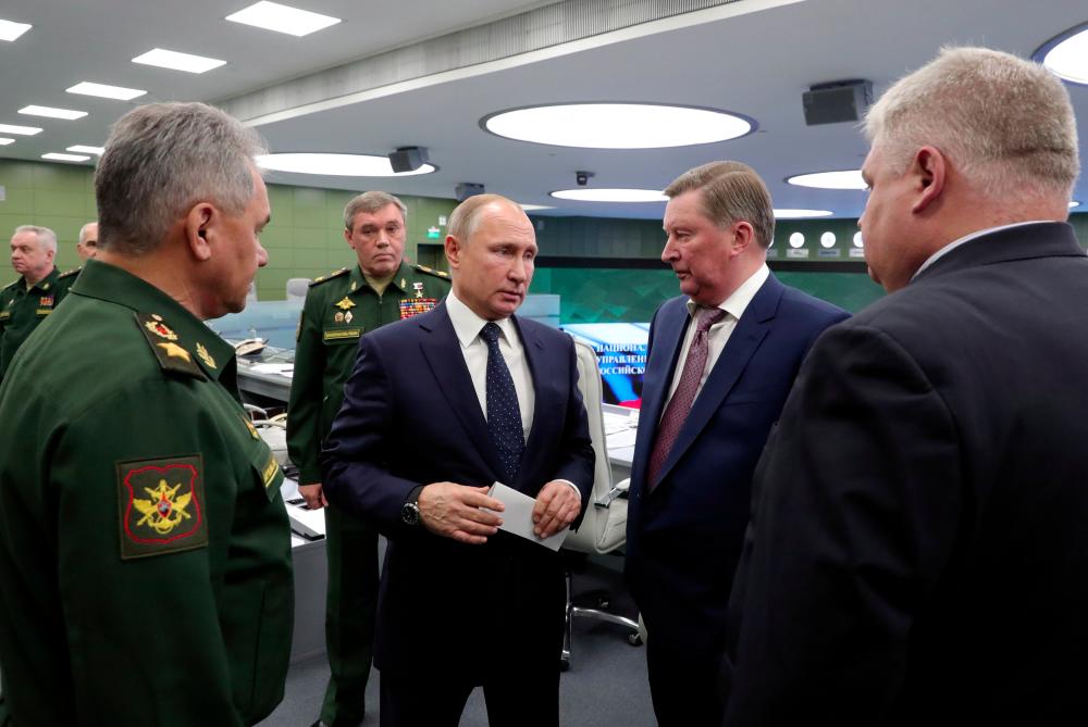 Russia's President Vladimir Putin (C) speaks with Special Presidential Representative for Environmental Protection, Ecology and Transport Sergei Ivanov (R2), Defence Minister Sergei Shoigu (L) and Chief of the General Staff of Russian Armed Forces Valery Gerasimov (L2, back) as he visits the National Defence Control Centre (NDCC) to oversee the test of a new Russian hypersonic missile system called Avangard, which can carry nuclear and conventional warheads, with Chief of the General Staff of Russian Armed Forces Valery Gerasimov seen nearby, in Moscow, Russia Dec 26, 2018. — Sputnik / Kremlin via Reuters