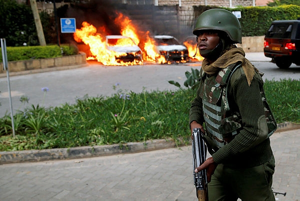 A policeman runs past burning cars at the scene where explosions and gunshots were heard at the Dusit hotel compound, in Nairobi, Kenya Jan 15, 2019. — Reuters