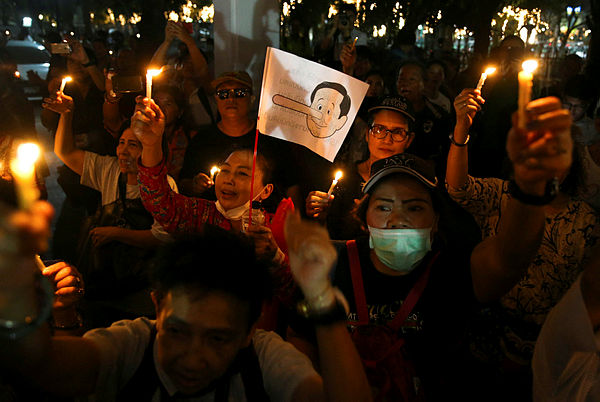 A placard mocking Thailand’s Prime Minister Prayuth Chan-o-cha as Pinocchio is seen as activists hold up candles while gathering to demand quick elections to end military rule at a university in Bangkok, Thailand, Jan 19, 2019. — Reuters