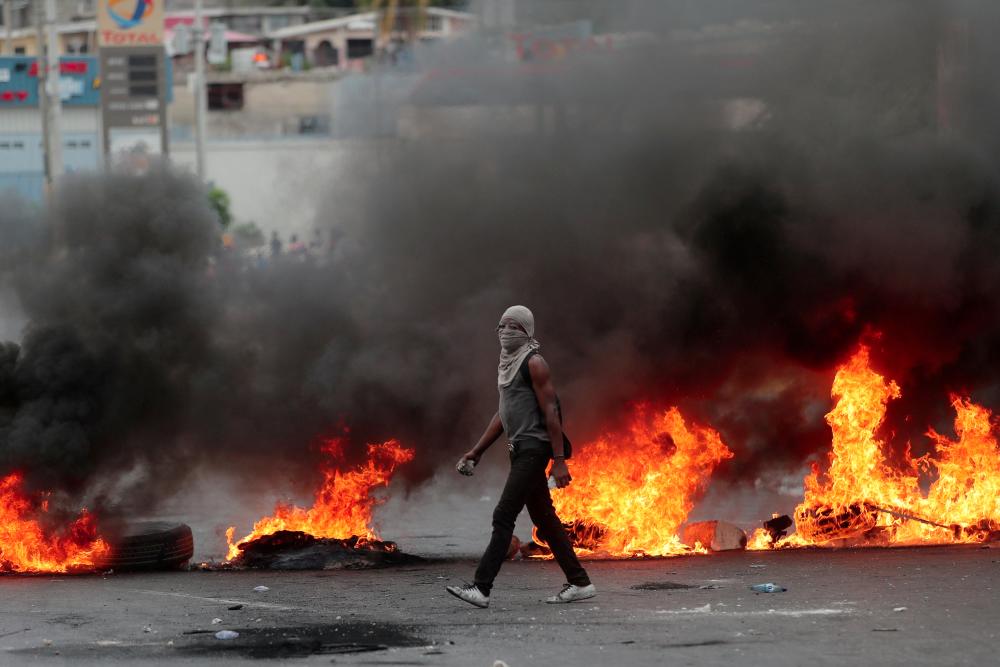 A demonstrator walks past a burning barricade during anti-government protests in Port-au-Prince, Haiti, on Feb 15, 2019. — Reuters