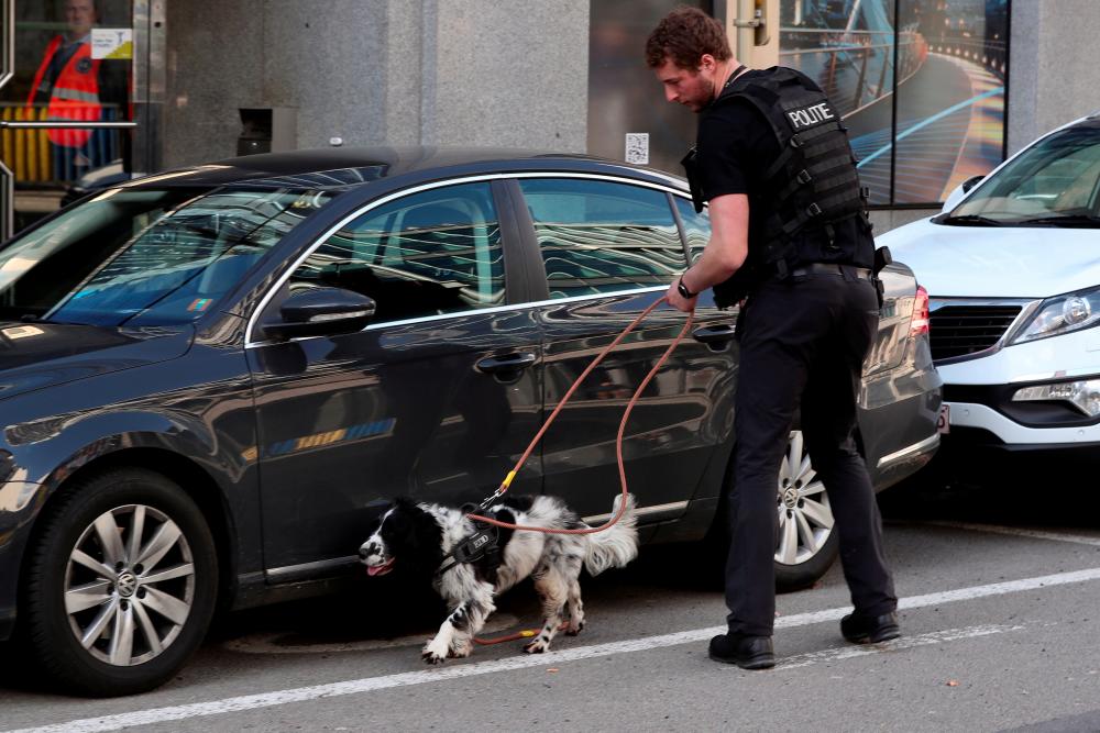 A police officer with a sniffer dog search around a vehicle after a bomb alarm in a building near to European Commission headquarters in Brussels, Belgium, March 19, 2019. — Reuters