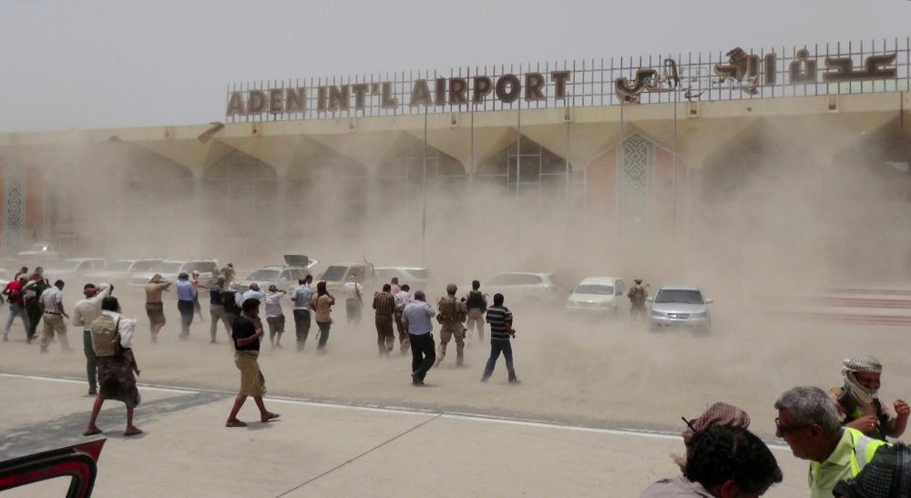 People seek cover from rising dust as a Qatari military cargo plane carrying aid lands at the international airport of Yemen's southern port city of Aden Aug 1, 2015. — Reuters