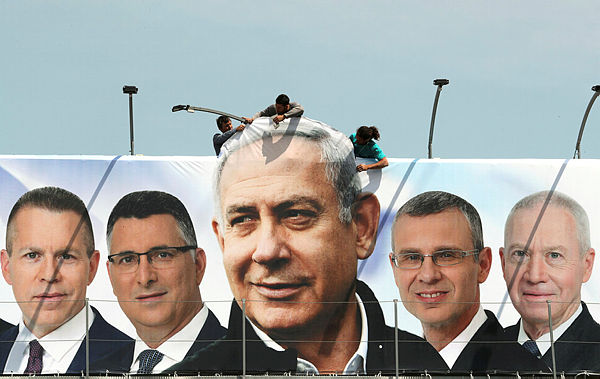 Labourers work on hanging up a Likud election campaign banner depicting Israeli Prime Minister Benjamin Netanyahu with his party candidates, in Jerusalem March 28, 2019. — Reuters