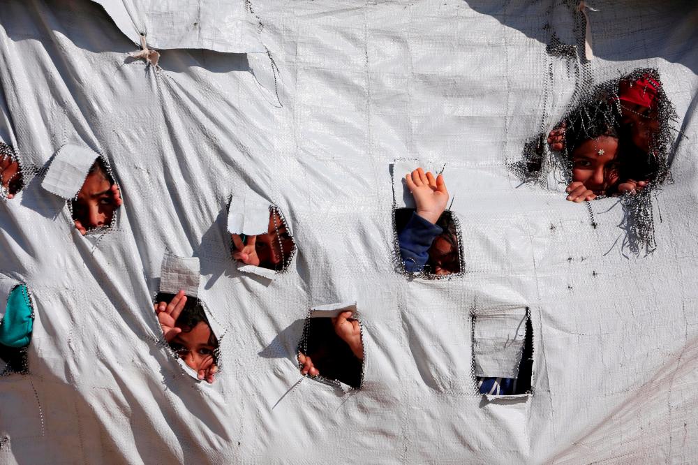 Children look through holes in a tent at al-Hol displacement camp in Hasaka governorate, Syria on April 2, 2019. — Reuters