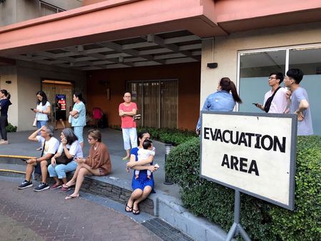 Residents sit outside after being evacuated from the condominium building after an earthquake in Makati City, Philippines, April 22, 2019. — Reuters