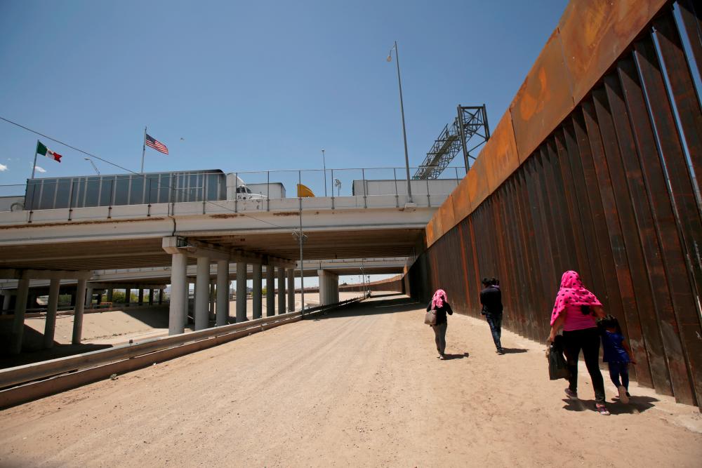A group of Central American migrants walk next to the US-Mexico border fence after they crossed the borderline in El Paso, Texas, US on May 15, 2019. — Reuters