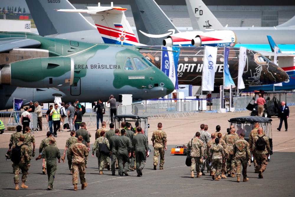 Soldiers walk past aircrafts on static display, at the eve of the opening of the 53rd International Paris Air Show at Le Bourget Airport near Paris, France. — Reuters
