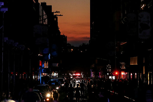 People walk along a dark street near Times Square area, as a blackout affects buildings and traffic during widespread power outages in the Manhattan borough of New York, US, July 13, 2019.