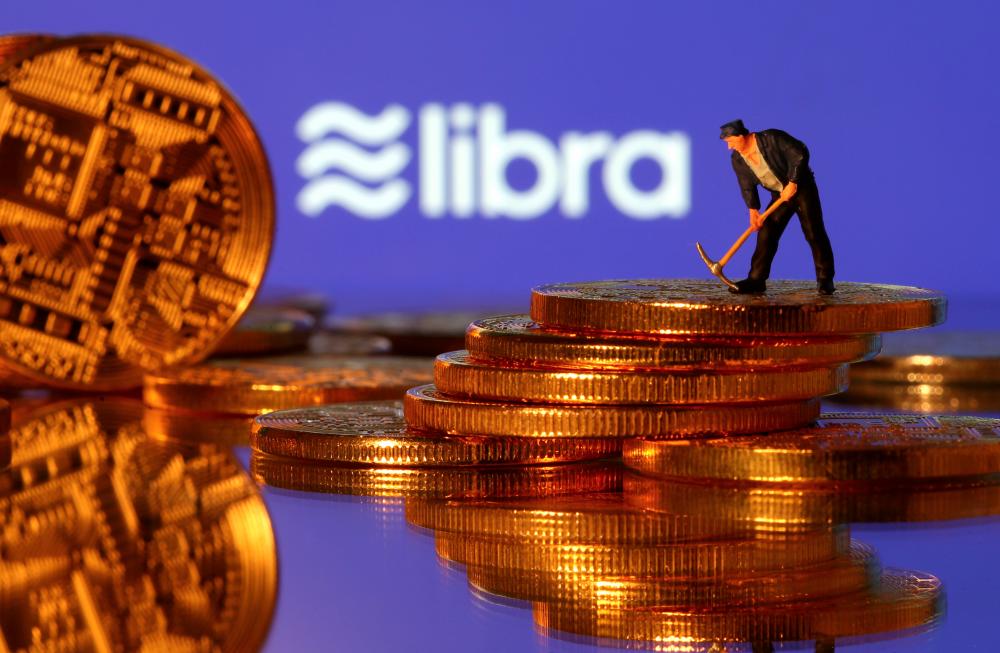 A small toy figure stands on representations of virtual currency in front of the Libra logo in this illustration picture, June 21, 2019. — AFP