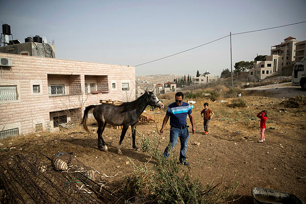 Ismail Obeideh walks with his horse near his home in the Palestinian village of Sur Baher, which sits on either side of the barrier in East Jerusalem and the Israeli-occupied West Bank, on July 17 — Reuters