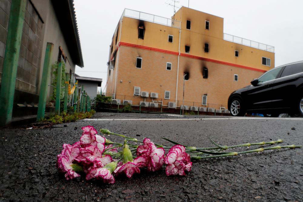 Flowers are placed in front of the torched Kyoto Animation building to mourn the victims of the arson attack in Kyoto, Japan, July 19, 2019. — Reuters