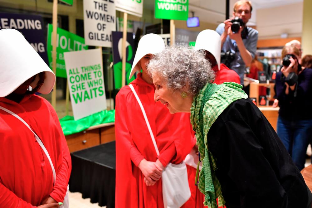 Author Margaret Atwood speaks with people dressed as hand maidens from The Handmaid’s Tale, after reading an extract from her new novel The Testaments during the book launch at a book store in London, Britain September 9, 2019. REUTERS/Dylan Martinez