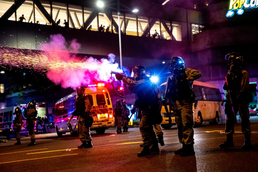 A riot police officer fires a tear gas canister toward anti-government protesters during a demonstration in the Tseung Kwan O residential area in Kowloon, Hong Kong, China, Oct 7, 2019. — Reuters