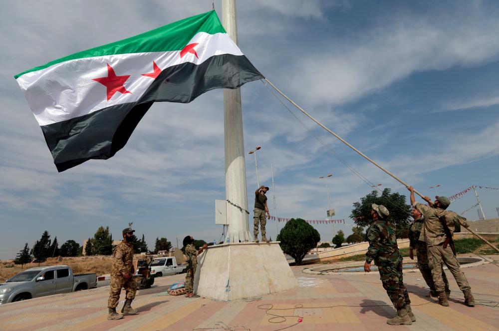 Turkey-backed Syrian rebel fighters raise the Syrian opposition flag at the border town of Tel Abyad, Syria, Oct 14, 2019. — Reuters